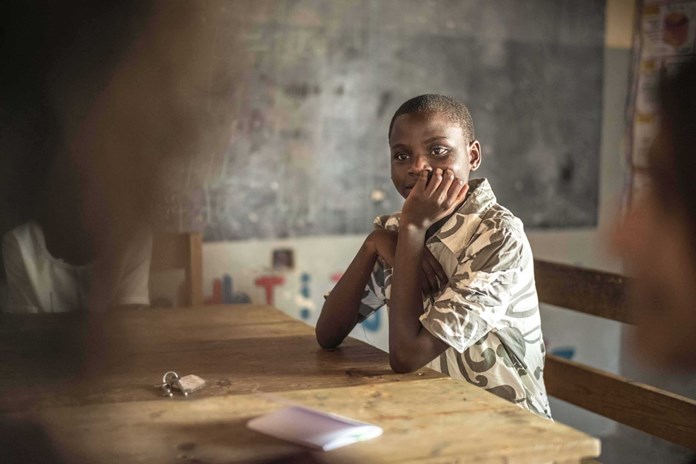 A young Tanzanian girl smiling in her classroom.