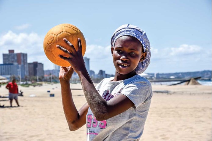 A young women from Umthombo in South Africa playing Volley Ball on the beach in Durban.