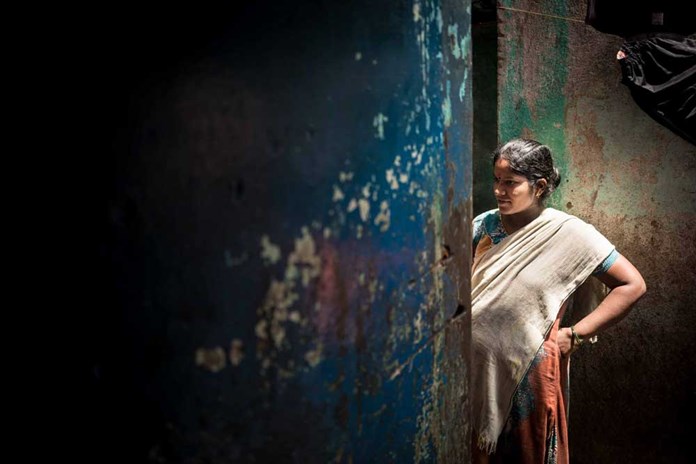 A women from a pavement-dwelling community in India stands in the darkness.