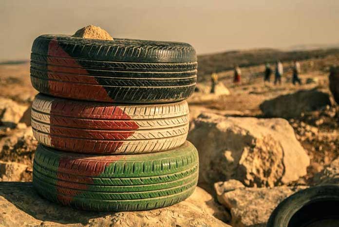 Three old car tyres painted with the Palestinian flag.