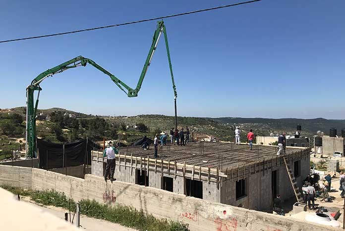 Concrete being poured onto the roof of a new home being rebuilt in the West Bank.
