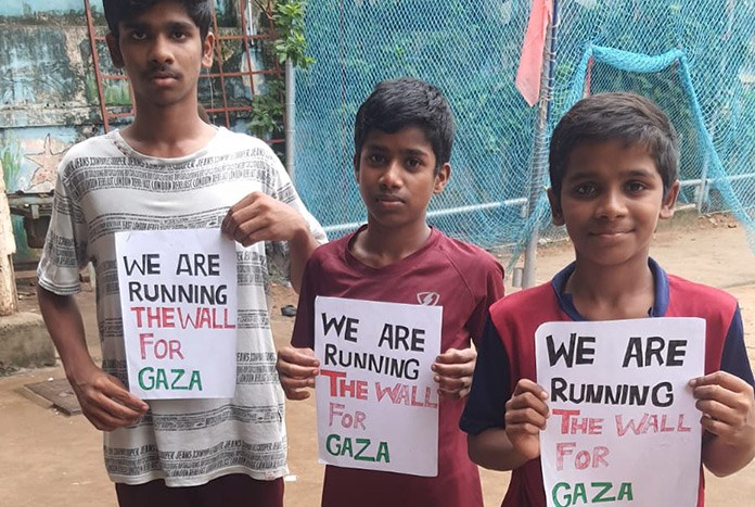 Three young Indian boys hold up signs that read, "We are running the Wall for Gaza."