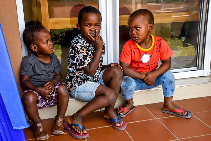 Three young South African children sitting outside a building in Durban.