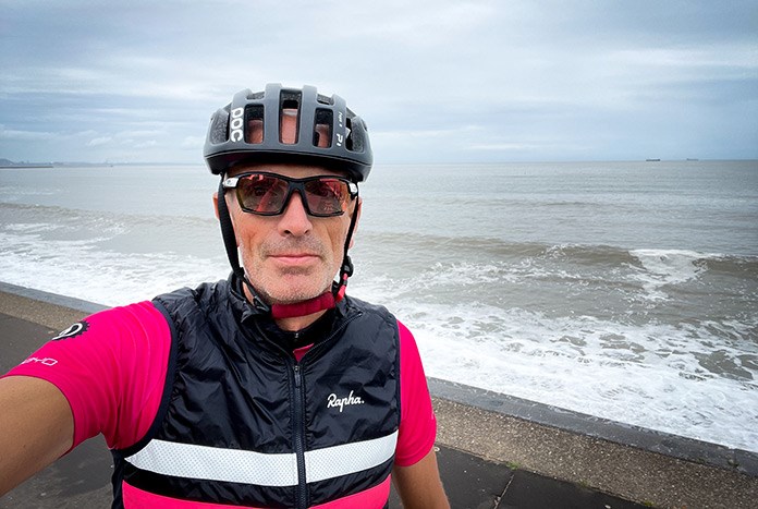 Amos Trust Director Chris Rose wearing his cycling gear on a beach.