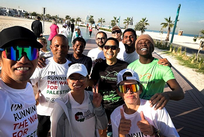 A group of runners in Dubai wearing Run The Wall T-shirts and smiling.