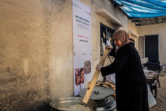 A woman stirs a large cooking pot full of rice in Gaza.