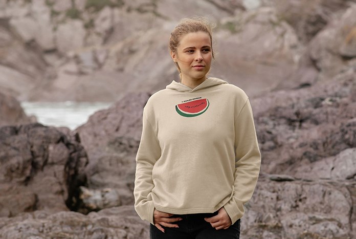 A young woman wears an oat-coloured Khaled Hourani watermelon hoodie by Amos Trust.