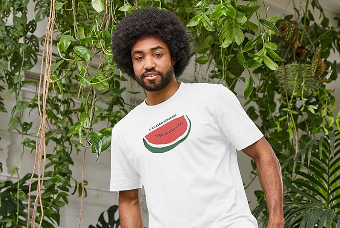 A young man wears a white Khaled Hourani watermelon T-shirt by Amos Trust.