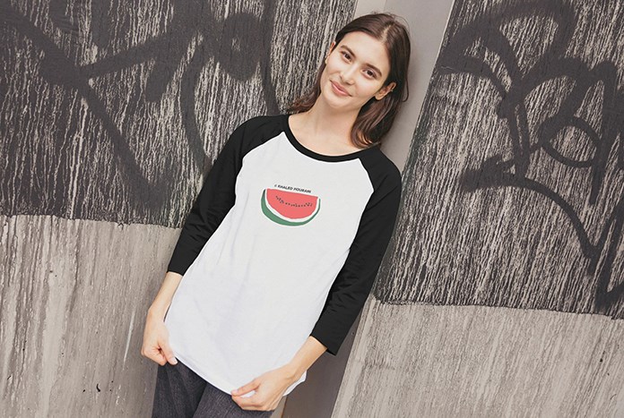 A young woman wearing an Amos Trust watermelon baseball shirt by Khaled Hourani.