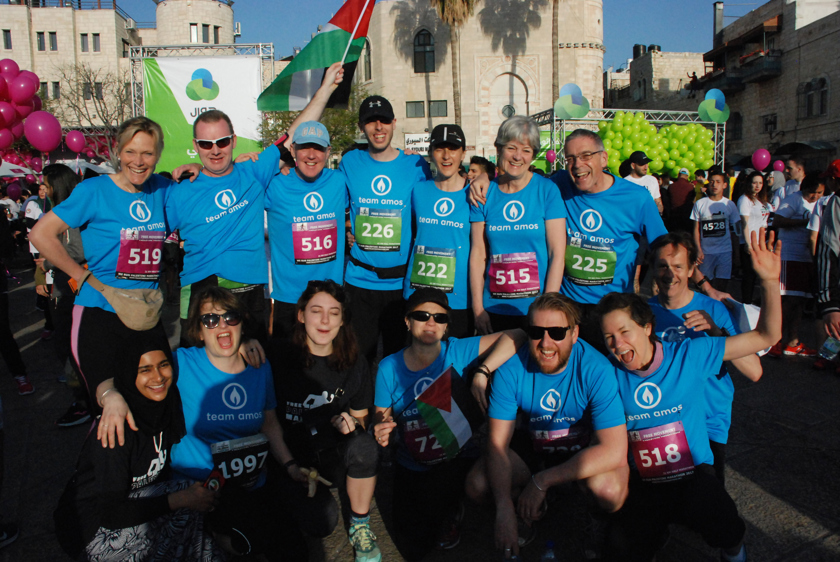 A group of smiling Amos Trust runners from the UK before the Palestine Marathon begins.