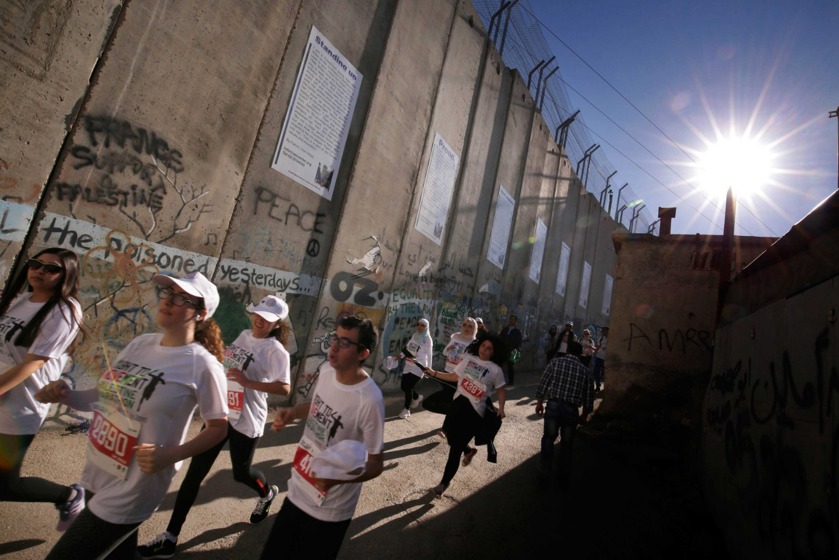 Participant sin the Palestine Marathon running by the illegal Separation Wall in Bethlehem.